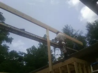 Carpenter setting a ridge beam over a new addition frame — Ice Dam Removal by Roofing Brothers in Farnham