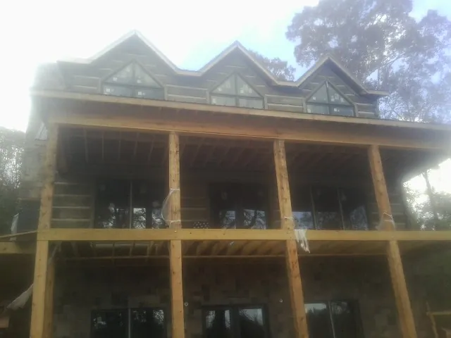 Dormers and porch framing on a large log home under construction — Roof Coating work by our crew in Farnham