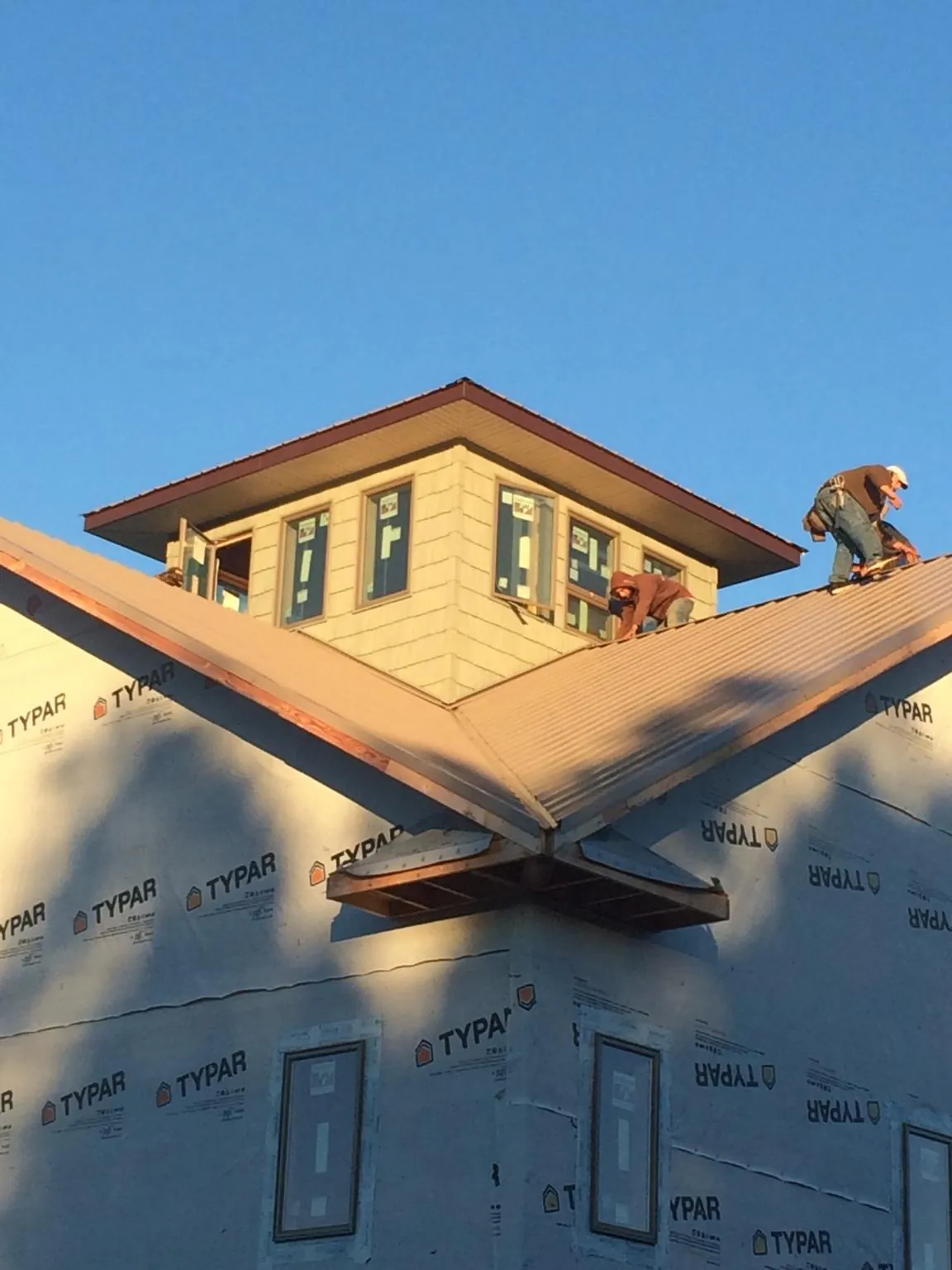 Roofers working around a rooftop cupola on a new metal roof at sunset — Roof Waterproofing in Farnham by Roofing Brothers